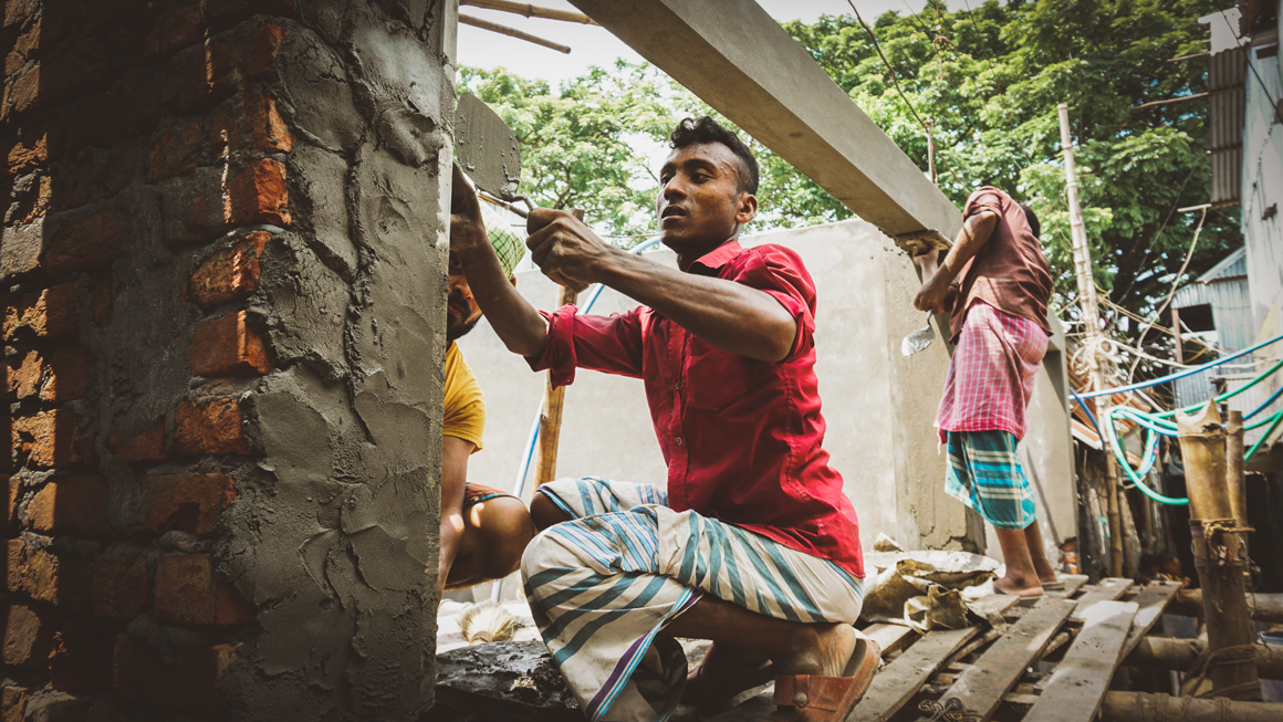 A man constructs a new building out of brick and cement in Ershadnagar. Image by Tasfiq Mahmood