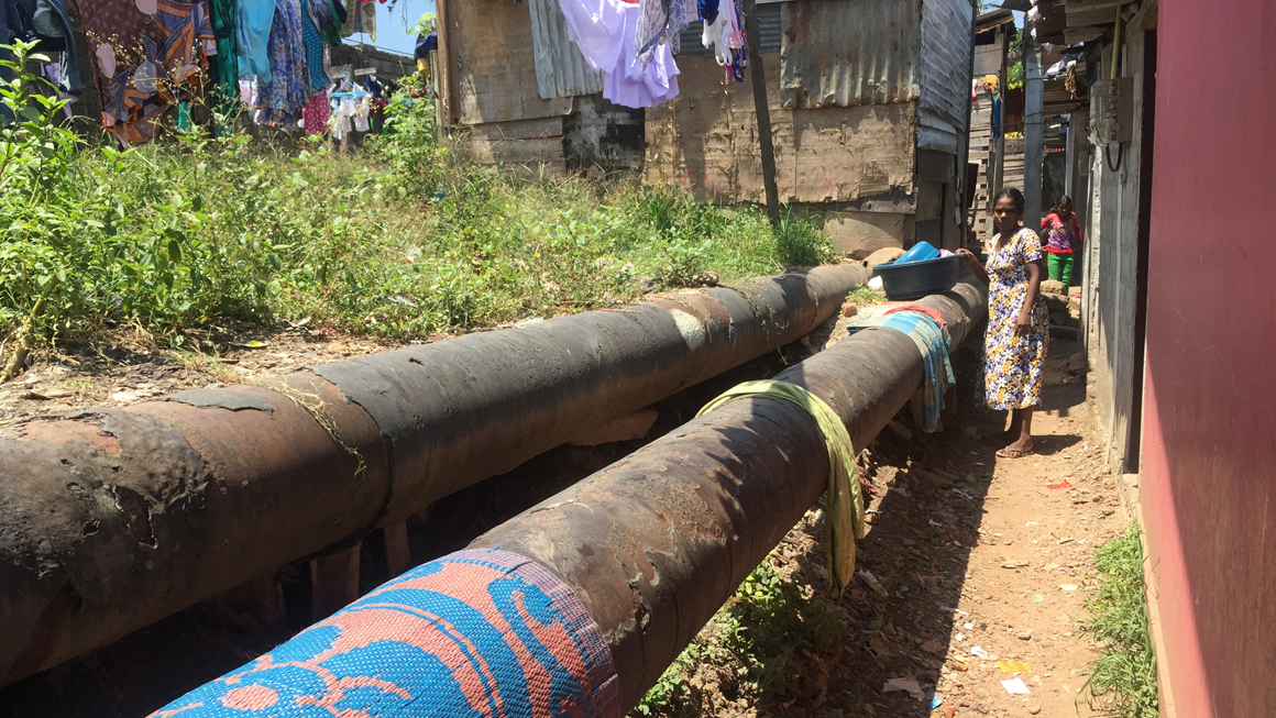 Rugs dry over the top of a large water pipe in Lunupokuna, one of the study communities. Image by Abdullah Azam.