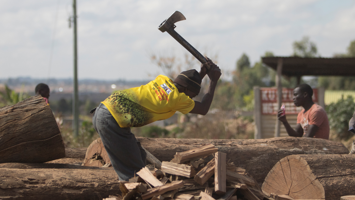 A man cutting wood for fuel in Epworth, Harare. Image by Wilfred Kajese