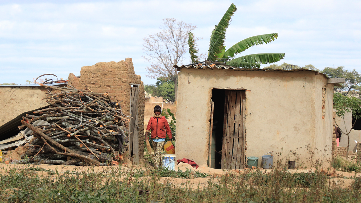 A woman walks between two shelters in Hopley, Harare. Image by Wilfred Kajese