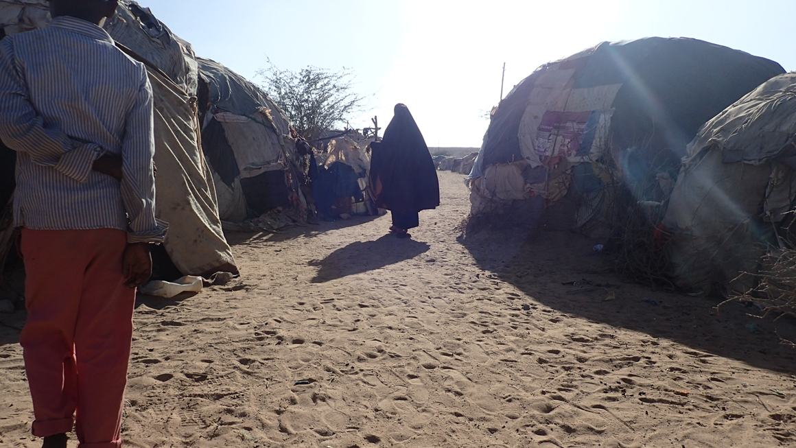 A woman walks in between the structures of Digaale camp. Image by Laura Hammond